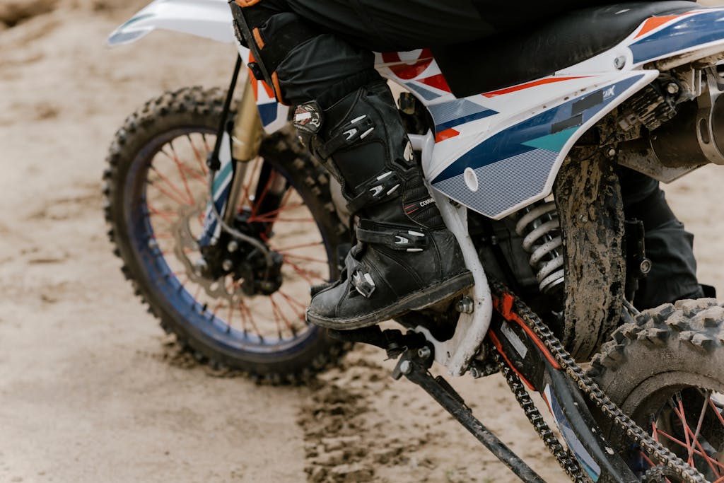 Close-up of a rider performing motocross on a dirt bike on sandy terrain.